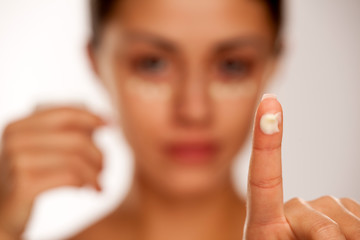 beautiful young woman with moisturizer on her fnger on white background