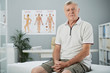Portrait of aged man sitting on bed in office of osteopath