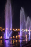 Fototapeta Tęcza - Colored luminous fountains in the middle of the lake at night.
