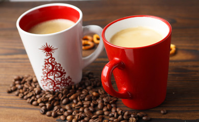 Two cups of coffee, grains of coffee and cookies on a wooden table.