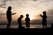 © No-Te - The silhouette of kids and mother at the beach in evening.