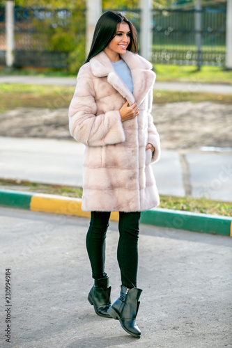 Fotografie, Tablou Beautiful sexy brunette in a light fur coat and black pants walks down the stree
