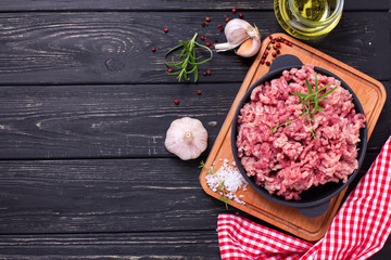 Wall Mural - Raw minced meat in bowl  with ingredients for cooking on  black table.