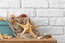 Starfish, Seashells And Pebbles As Decorations On Table Near White Brick Wall