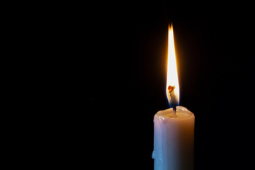 a lonely burning candle in the darkness