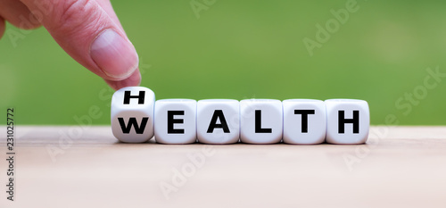 Fotografía Hand is turning a dice and changes the word Health to Wealth