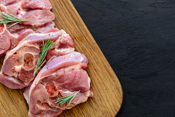 Raw turkey steak meat with bone on wooden board background