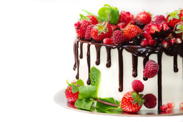 white cake poured with brown chocolate and decorated with berries on an isolated white background