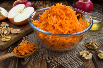 Wall Mural - Grated carrot in the glass bowl and ingredients for salad on the rustic wooden  background