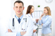 © rogerphoto - Friendly male doctor  on the background with patient  and physician