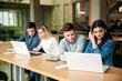 © Aleksandr - Group of college students studying in the school library, a girl and a boy are using a laptop and connecting to internet
