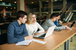 © Aleksandr - Group of college students studying in the school library, a girl and a boy are using a laptop and connecting to internet