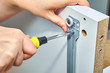 Furniture assembler tightens screw in drawer slides.