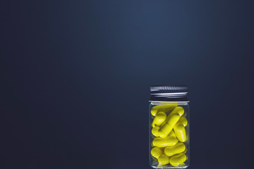 Wall Mural - Yellow capsules in a transparent glass bottle of medium size, isolated on a dark background. Natural supplements for health. Studio lighting