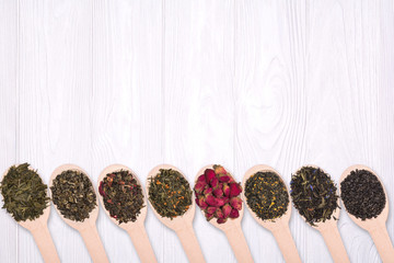 Wall Mural - Set of dry herbal teas in wooden spoons on a white background. View from above.