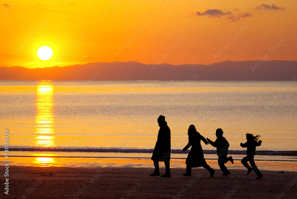シルエットの四人家族が歩く夕日が沈む美しい海岸 Stock-foto | Adobe