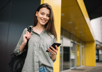 Beautiful happy woman using mobile phone and application for online shopping with discount sales. Positive hipster blogger streaming video online, walking on the street