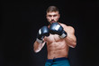© satyrenko - Strong muscular boxer in black boxing gloves. Isolated on black background.