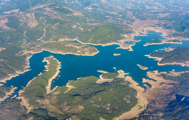 Aerial view, birds eye view of the lake among wooded hills. Summer sunny day