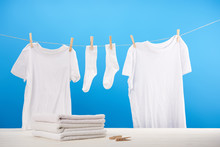 Pile On Clean Towels, Clothespins And White Clothes Hanging On Rope On Blue