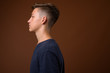 © Ranta Images - Studio shot of young handsome teenage boy against brown backgrou
