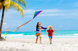 © famveldman - Child with kite. Kids play. Family beach vacation.