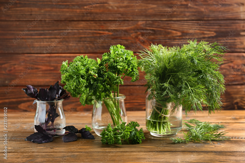Jars with fresh aromatic herbs on wooden table