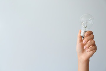 Wall Mural - Female hand with eco light bulb on light background