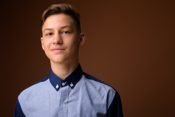 Studio shot of young handsome teenage boy against brown backgrou