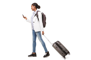 Wall Mural - Full body portrait of young black woman walking with suitcase and mobile phone