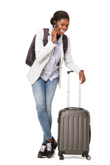 Canvas Print - happy young black woman with suitcase standing against isolated white background while talking on cellphone