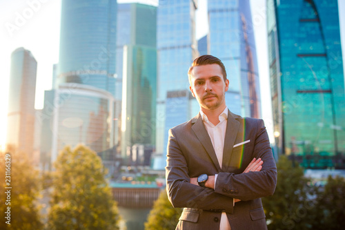 Fotomural Businessman looking on copy space while standing against glass skyscraper