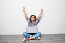 Portrait Of Happy Young Mixed Races Curly Woman Sitting On Floor With Laptop And Celebrate Win