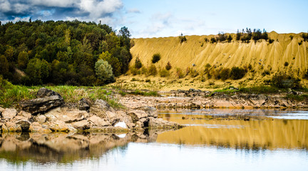 Sandy hills. Lake in the Sandy canyon. Warm colors background. Yellow sandstone textured mountain, white thin sand dune, bright sky. Sunshine landscape