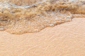 Wave of sea on the sand of beach. Holiday background. Vacation concept. Macro photo.