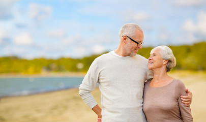 Wall Mural - old age, retirement and people concept - happy senior couple hugging over beach background