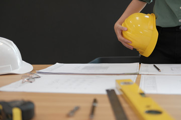 engineer architect worker holding safety helmet hardhat wtih construction blueprint on desk