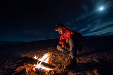 Wall Mural - While looking for meteorites at Atacama Desert we made a stop for sleeping in the middle of the amazing Atacama Desert. One man on a camp fire under the full moon light on a starry night. Chile
