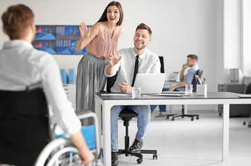 Canvas Print - Young man in wheelchair with colleagues at workplace