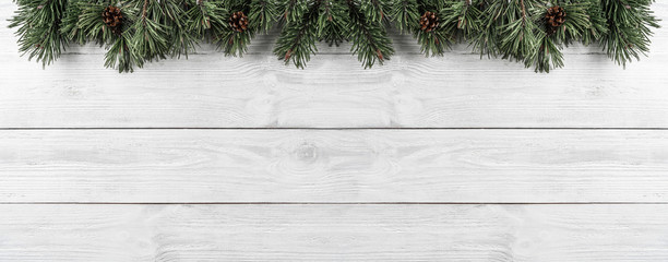 Wall Mural - Christmas Fir branches with pine cones on white wooden background. Xmas and Happy New Year theme. Flat lay, top view