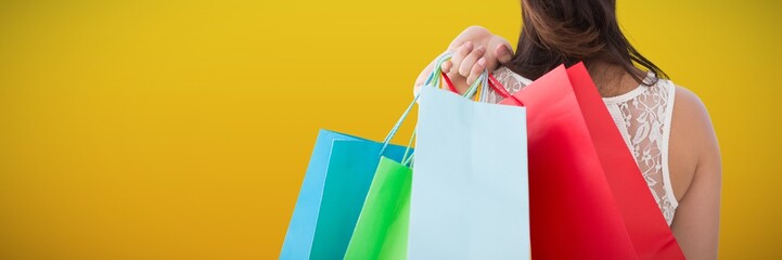 Poster - Composite image of rear view of brunette holding shopping bags