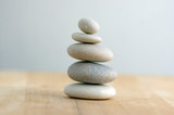 Fototapeta Desenie - Stone cairn on striped grey white background, five stones tower, simple poise stones, simplicity harmony and balance, rock zen