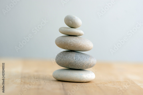 Fotografía Stone cairn on striped grey white background, five stones tower, simple poise st