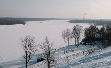 Winter city landscape with Smoking factory chimneys and winter park with walking people.