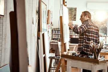 A painter in his studio working on a canvas at sunrise