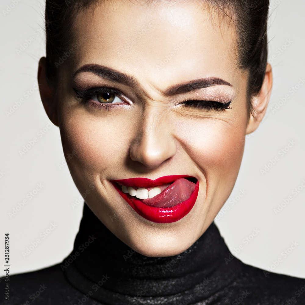 Young woman with bright face expression. Girl winks one eye - obrazy, fototapety, plakaty 
