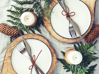 Wall Mural - Festive table setting among winter decorations and white candles. Top view, flat lay. The concept of a Christmas or Thanksgiving family dinner.