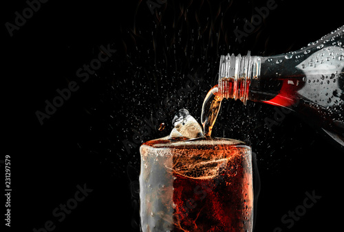 Pour soft drink in glass with ice splash on dark background. Tableau sur Toile