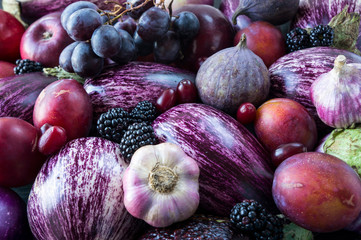 Background of fresh vegetables and fruits. Purple eggplant, backberries, grapes, plums, figs, apples, grape and garlic. Top view. Purple food.