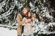 © Elizaveta - Young Caucasian boy and girl in love heterosexual couple have a date outdoors in a winter park on the background of a snowy conifer standing in an embrace. Man hugging woman valentines day